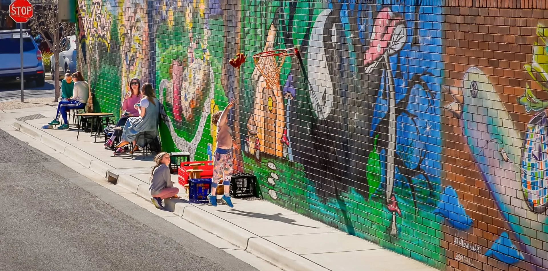 A painted mural along a Braddon laneway with people at a cafe table